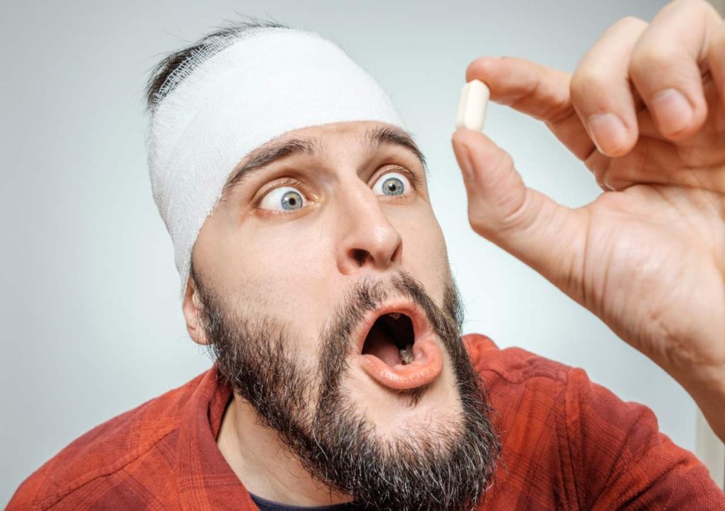 muž pozerá na bielu tabletku